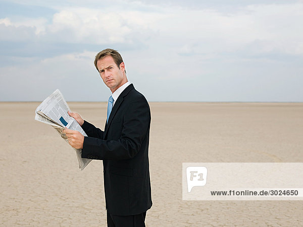 Geschäftsmann beim Lesen einer Zeitung in der Wüste