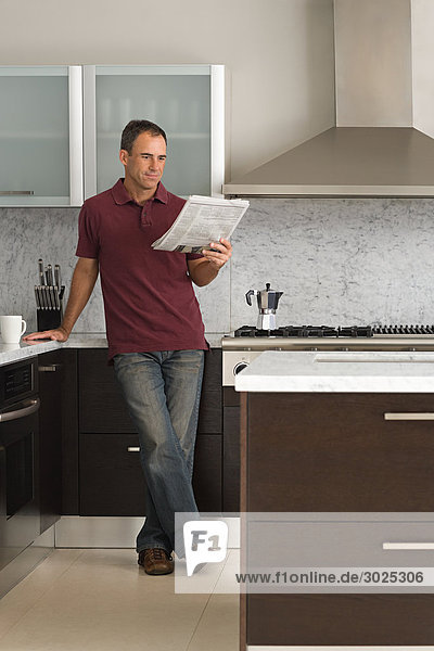 Man reading a newspaper in kitchen