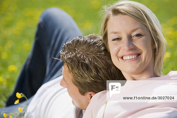 Paar auf der Wiese sitzend  Frau lächelnd