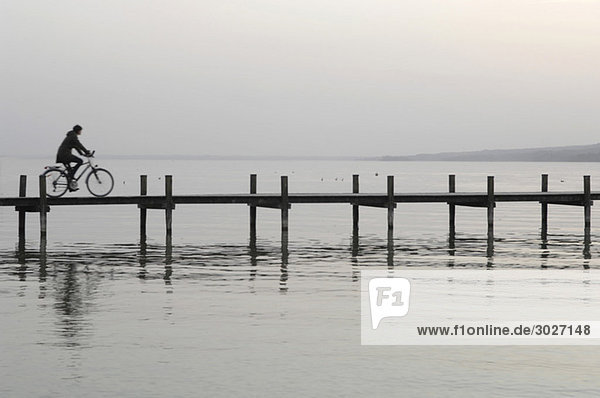 Starnberger See  Frau beim Radfahren über die Uferpromenade