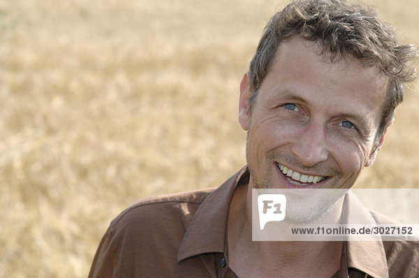 Mann im Feld stehend  lächelnd  Portrait