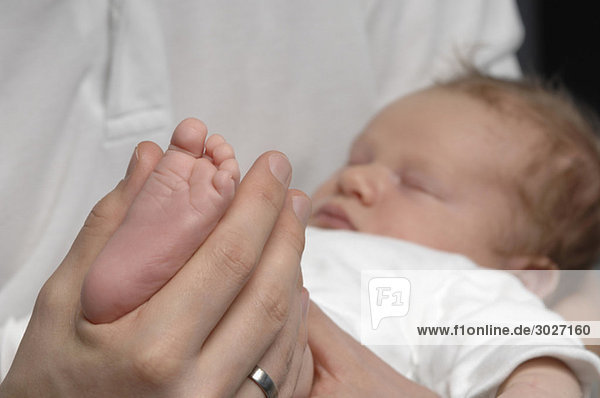 Baby boy (3 weeks) sleeping  Hand holding his foot  close up