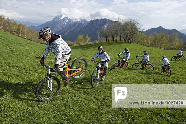 Italy  Lake Como  Group of mountain bikers riding across meadow