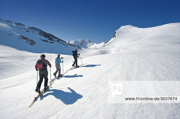 Austria  Salzburger Land  Altenmarkt  Zauchensee  Three persons cross country skiing in mountains  rear view