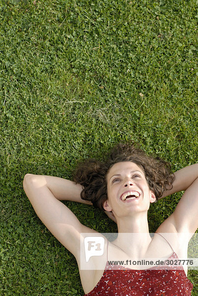 Young woman lying in meadow  laughing  elevated view  portrait