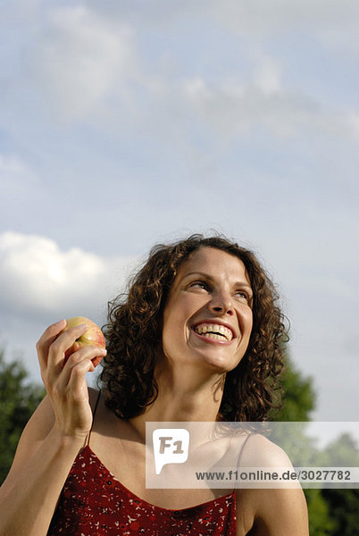 Junge Frau hält Apfel  lächelnd  Portrait