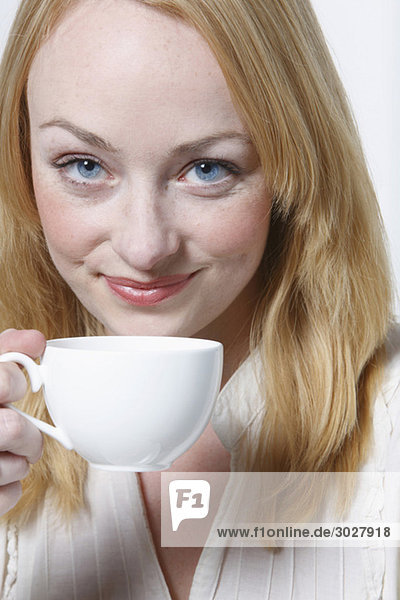 Junge Frau hält Tasse Kaffee  lächelnd  Portrait