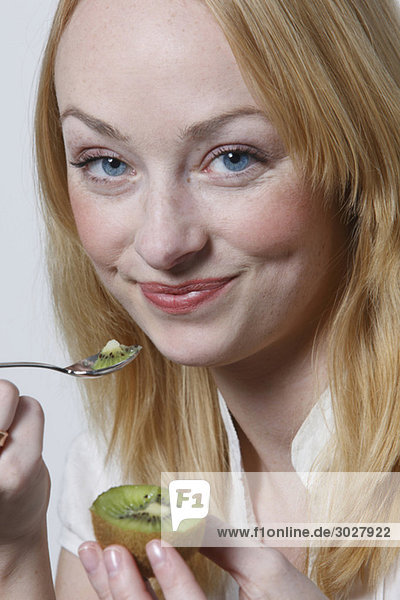 Junge Frau isst Kiwifrucht  Porträt