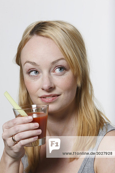 Junge Frau hält ein Glas Tomatensaft  Portrait