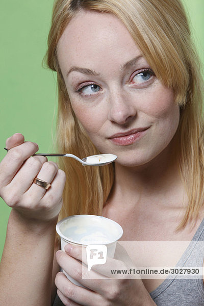 Junge Frau mit Joghurtbecher  Portrait