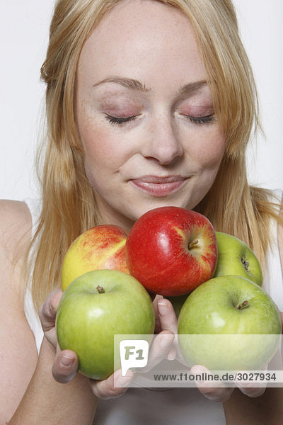 Junge Frau hält Äpfel  Augen geschlossen