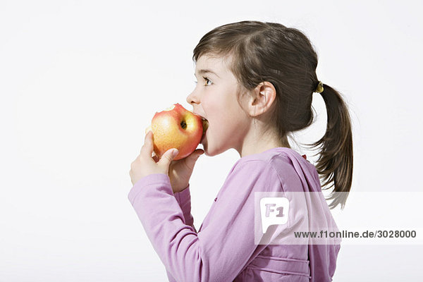 Girl (4-5) eating an apple  side view  portrait