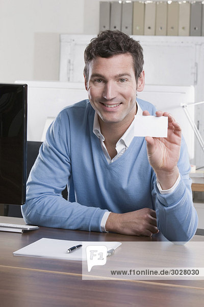 business man in office holding business card  smiling  portrait