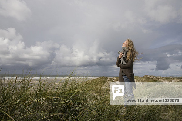 Germany  Schleswig Holstein  Amrum  Young woman on grassy sand dune