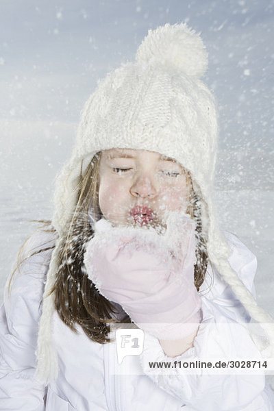 Girl (4-5) blowing snow off hand  eyes closed  portrait