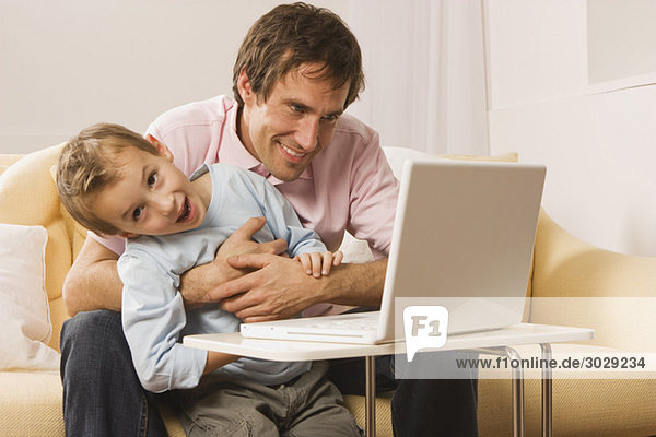 Father and son (4-5) using laptop