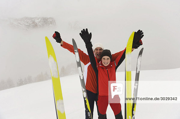 Italien  Südtirol  Paar in Winterkleidung  Jubel  Skier im Vordergrund