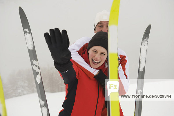 Italien  Südtirol  Paar in Winterkleidung  Lachen  Skier im Vordergrund