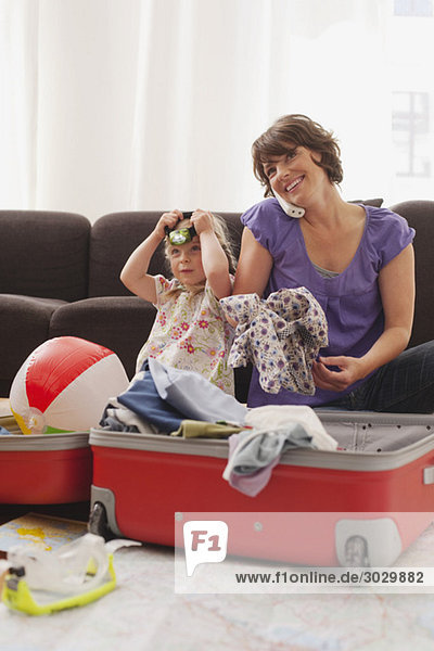 Deutschland,  Leipzig,  Mutter und Tochter (4-5) beim Kofferpacken,  Mutter per Telefon