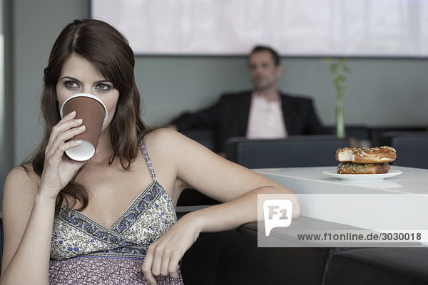 Junge Frau im Café trinkt Kaffee Mann im Hintergrund