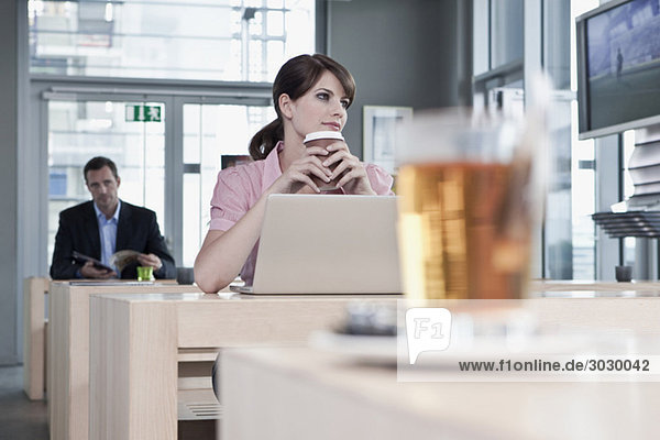 Junge Frau im Cafe mit Laptop  Mann im Hintergrund