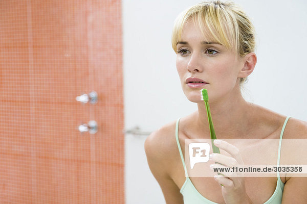 Spiegelung einer Frau im Spiegel mit Zahnbürste