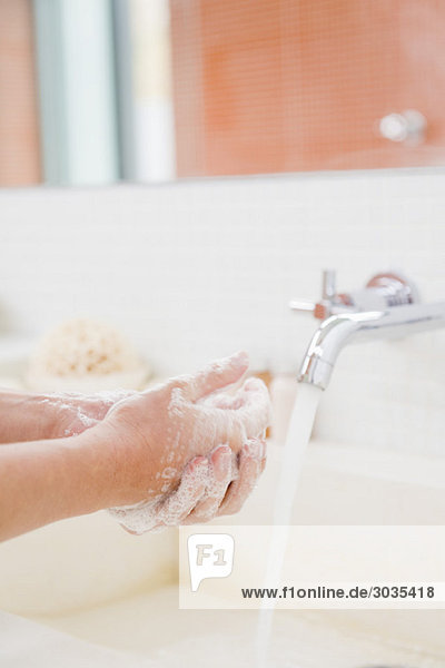 Frau beim Händewaschen im Bad