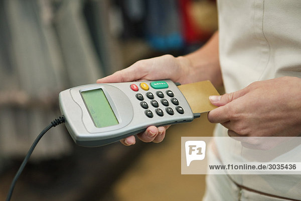 Mid section view of a woman using a credit card reader in a boutique
