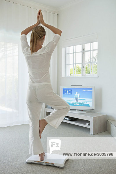 Frau beim Yoga vor dem Fernseher