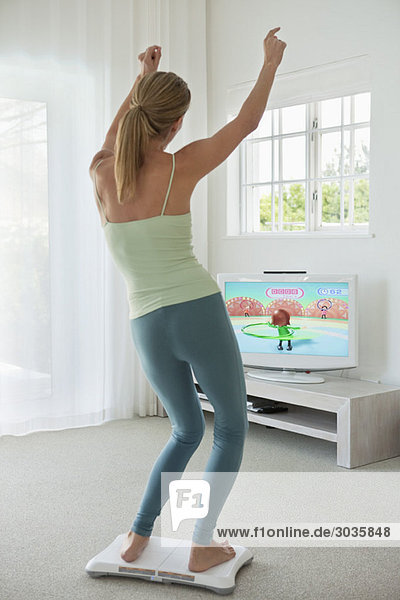 Woman doing step aerobics and watching TV