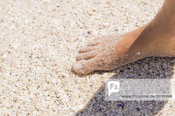 Close-up of a man's foot on sand