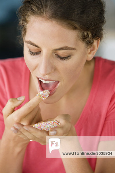 Frau isst farbiges Zuckergranulat