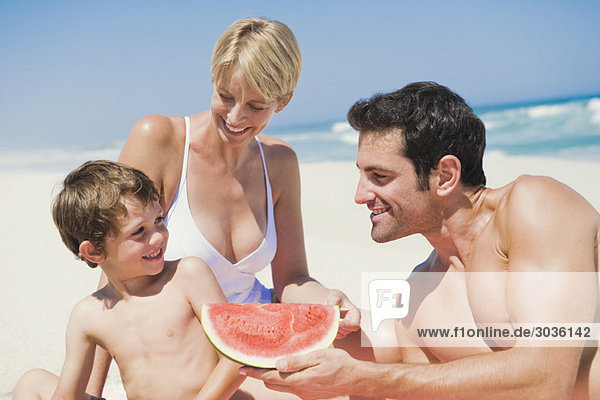 Familie genießt Wassermelone am Strand