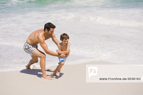 Mann spielt mit seinem Sohn am Strand
