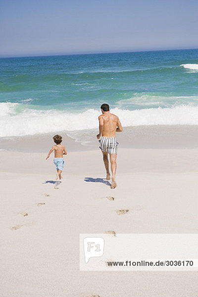 Mann,  der mit seinem Sohn am Strand läuft