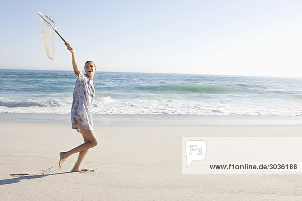 Frau mit Fischernetz am Strand