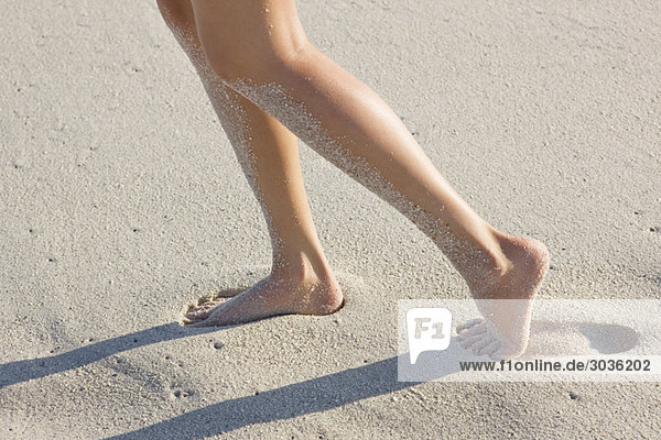 Low section view of a woman walking on the beach