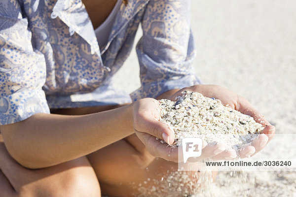 Frau spielt mit Sand am Strand