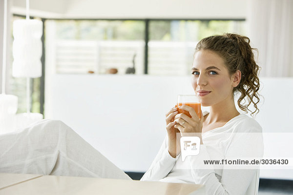 Porträt einer Frau  die Tomatensuppe trinkt und lächelt
