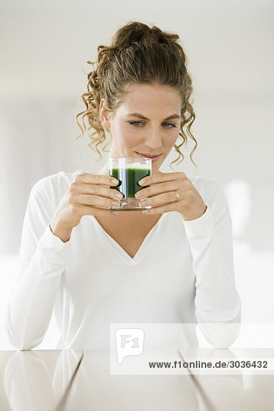 Woman holding a glass of pea soup