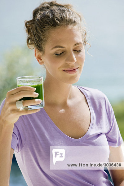 Close-up of a woman holding a glass of pea soup with her eyes closed