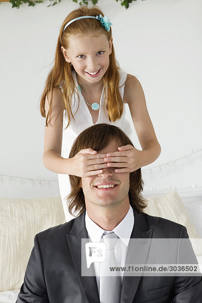 Girl covering man's eyes and smiling