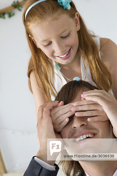 Girl covering man's eyes and smiling