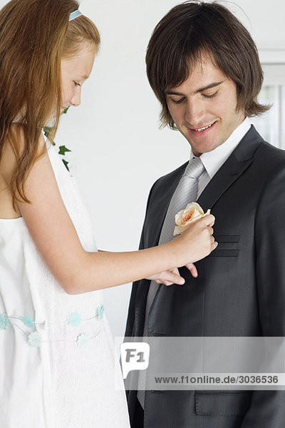 Girl pinning a corsage on a groom's tuxedo