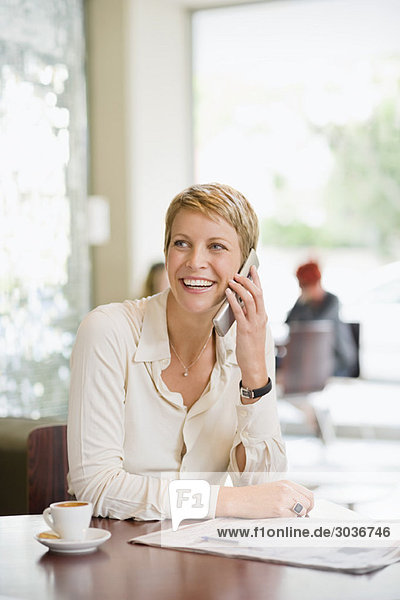 Geschäftsfrau sitzt in einem Restaurant und redet auf dem Handy