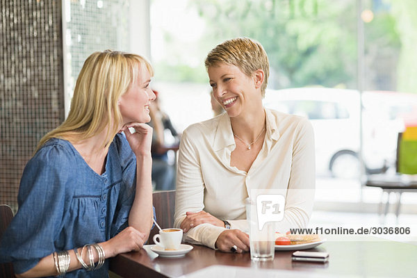 Zwei Frauen  die in einem Restaurant sitzen und lächeln.