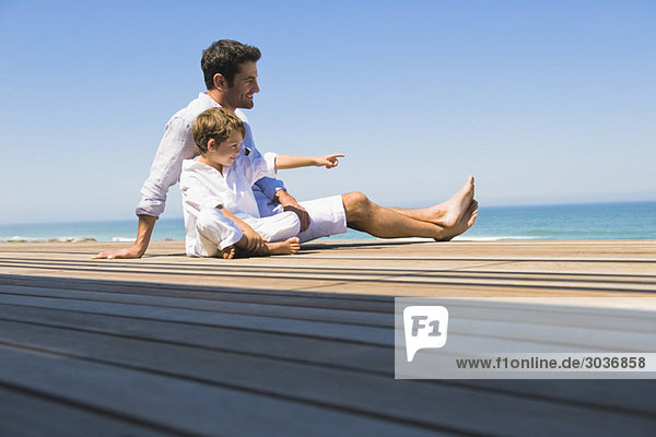 Man sitting on a boardwalk with his son