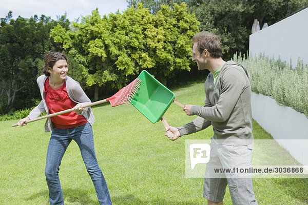Couple playing with gardening equipments in a lawn