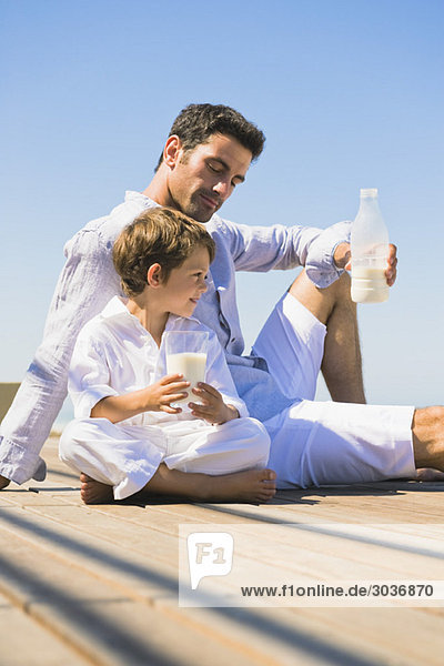 Der Mann und sein Sohn trinken Milch am Strand.