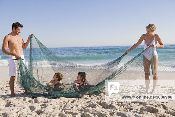Familienspiel mit einem Fischernetz am Strand